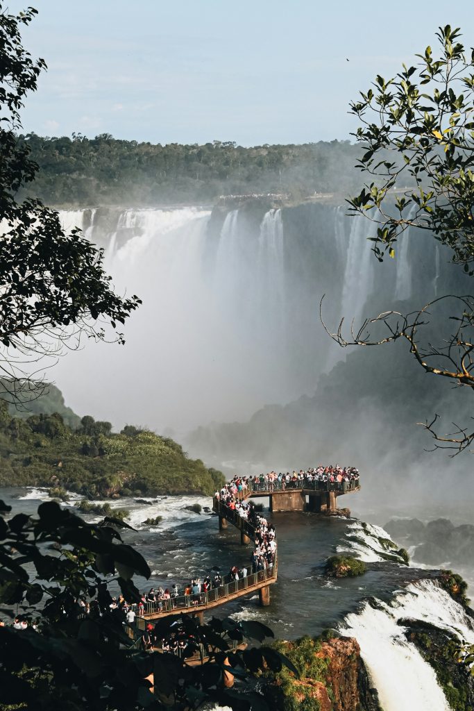 Loopbrug over de rivier met een waterval op de achtergrond