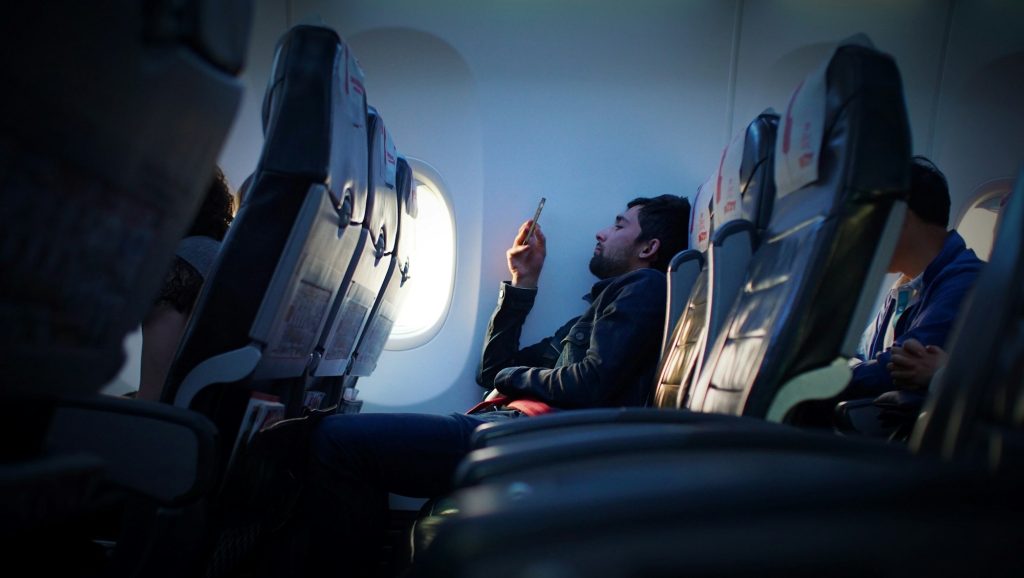 Reiziger met smartphone in het vliegtuig