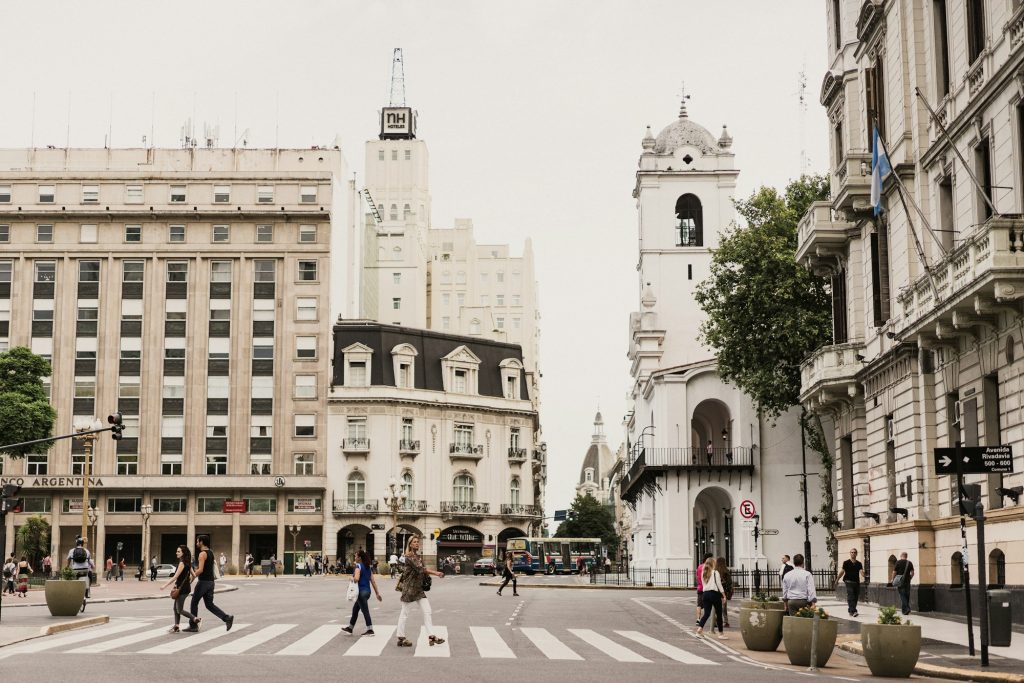 Vrouw steekt een straat over tussen hoge gebouwen in Buenos Aires